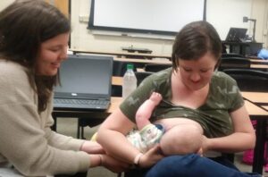 Breastfeeding consultant supports mother feeding with breast milk.