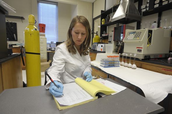 April taking detailed notes in a lab.