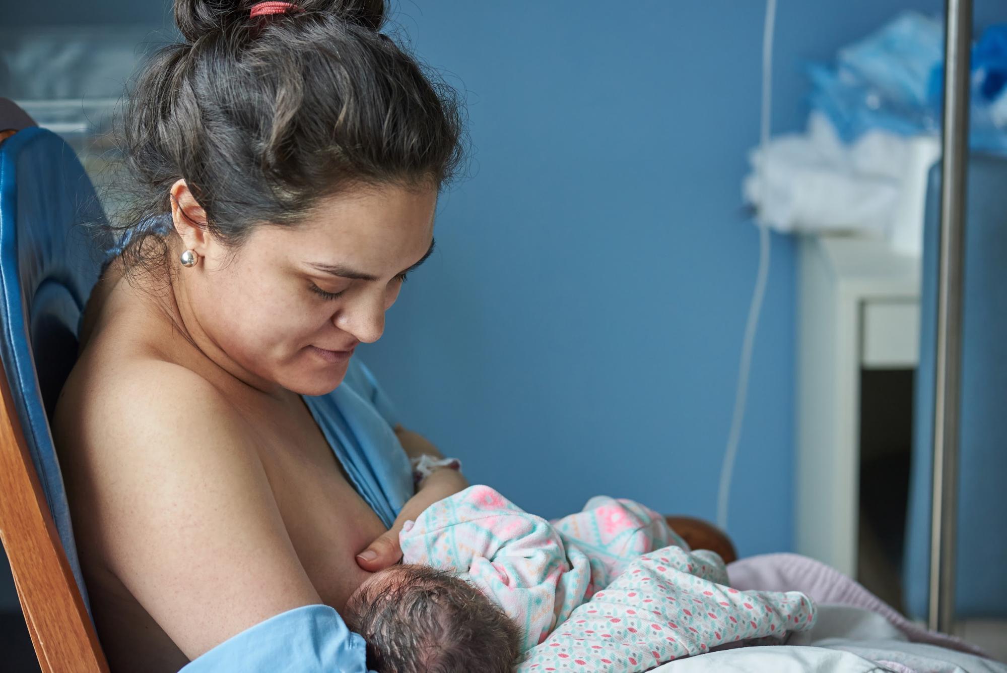 A Latina mother nurturing her newborn baby through breastfeeding in a hospital.