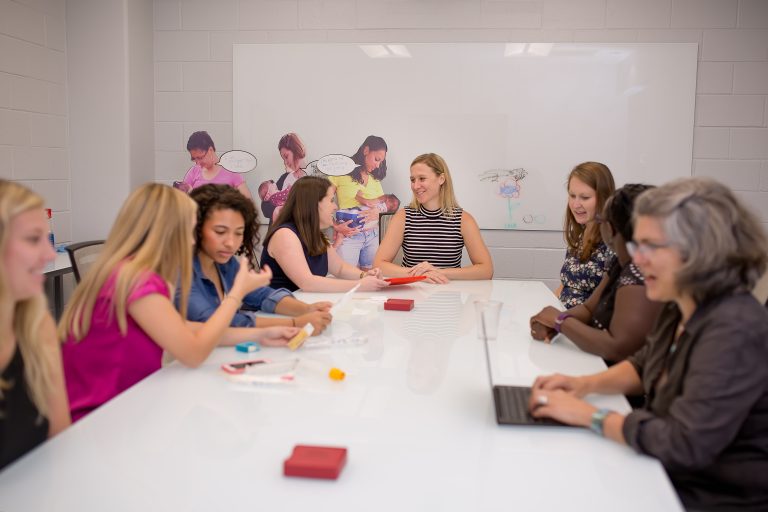 April and her coworkers sitting at a table for a meeting.
